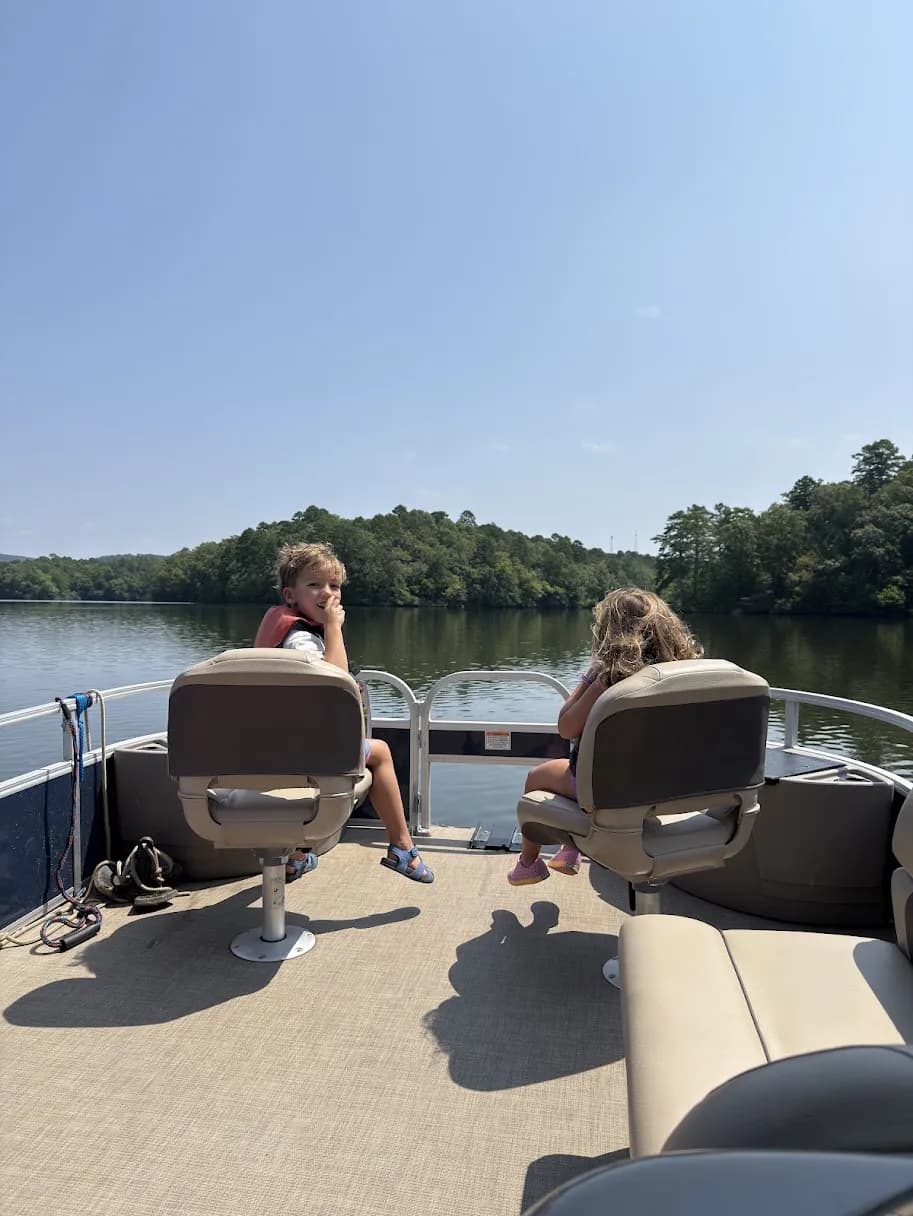 The kids in their life jackets on a pontoon boat on a quiet Arkansas lake