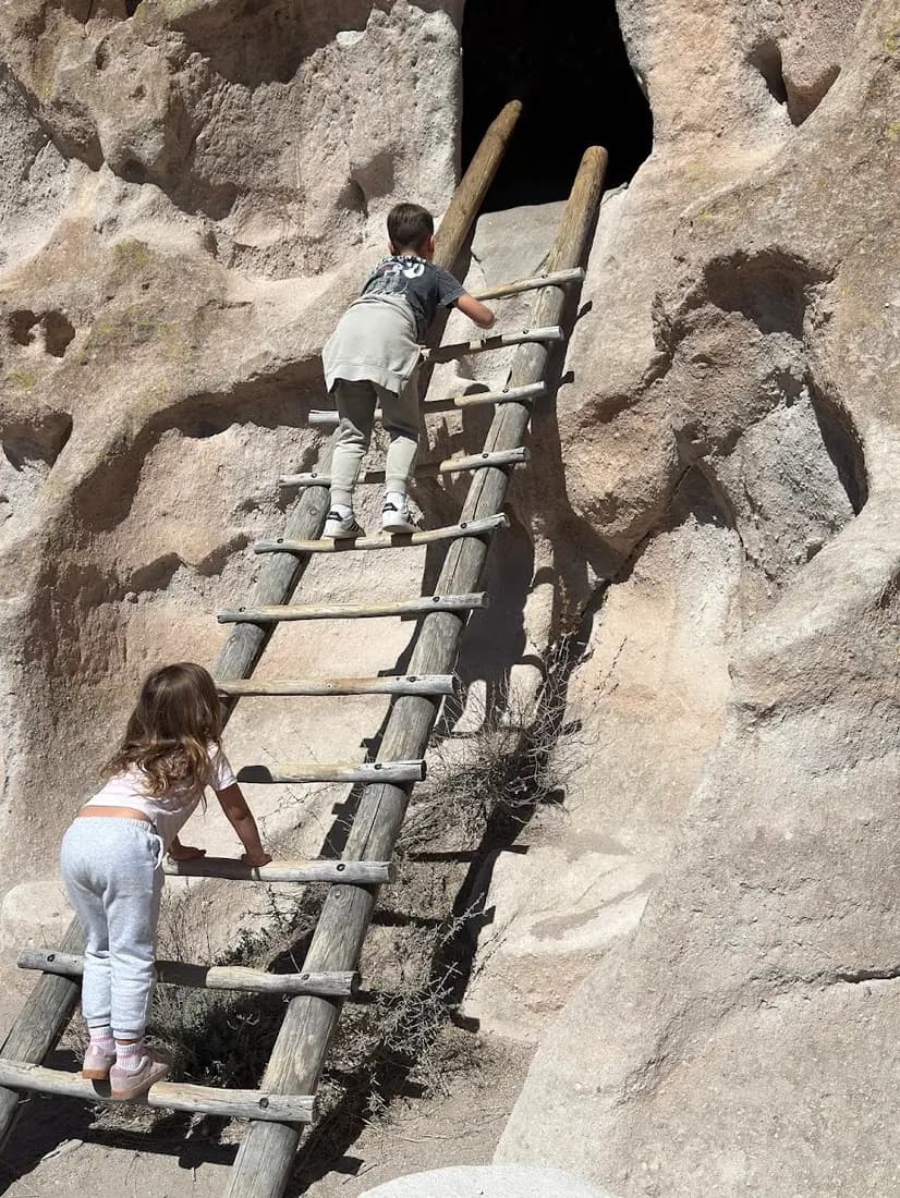 The kids climbing the wooden ladders to the cliff dwellings at Bandelier National Monument