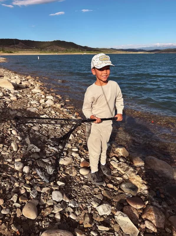 Our son holding up the landing net with his catch at a mountain lake