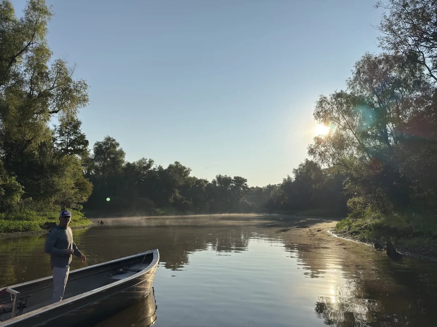 Morning mist rising off a Louisiana bayou, seen from the bow of a small boat