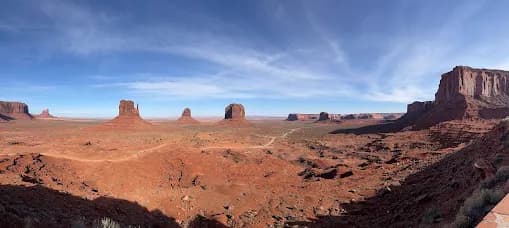 Panorama of the sandstone buttes of Monument Valley under a wide blue sky