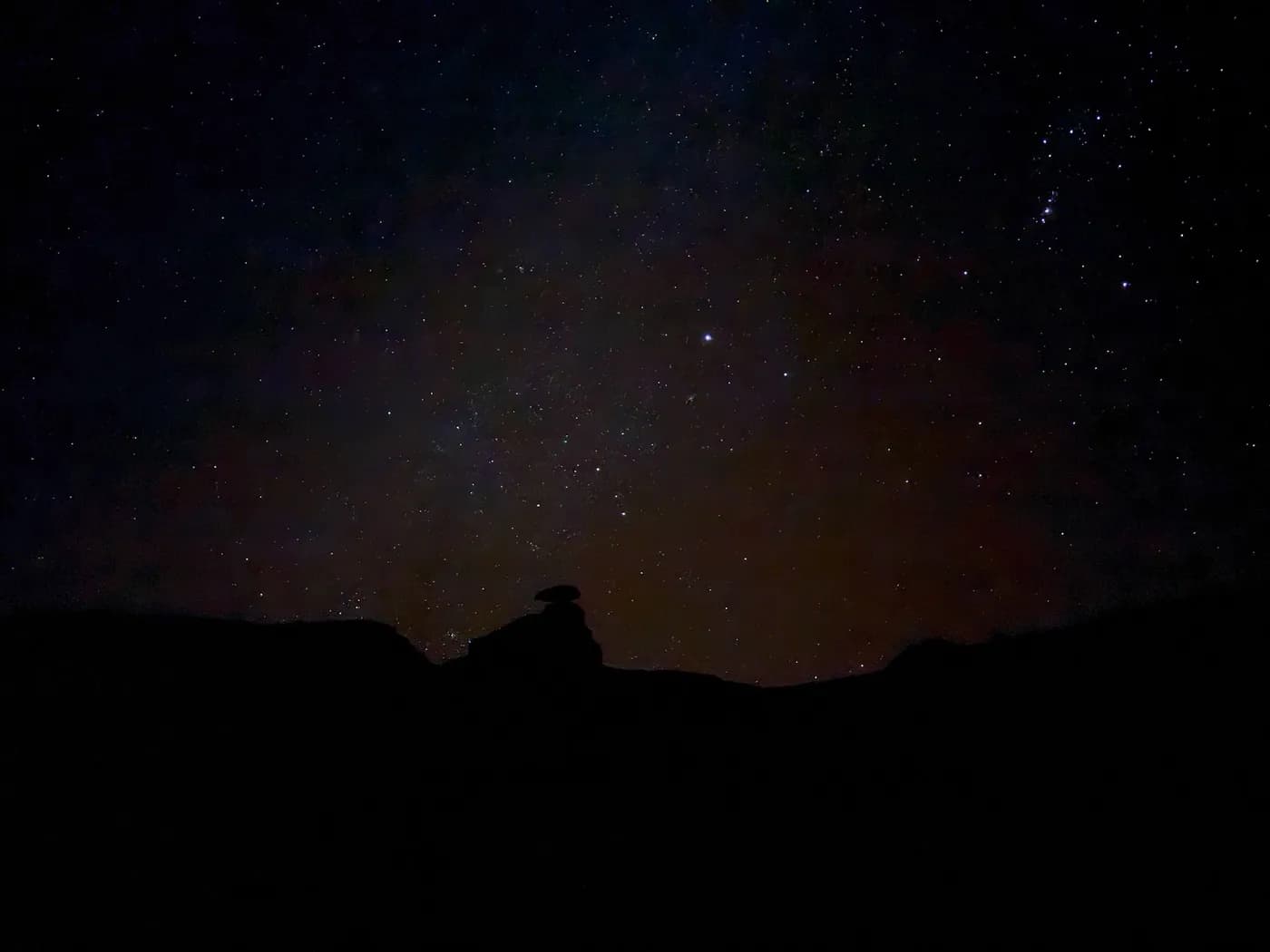 A star-filled night sky over the silhouette of the Utah desert